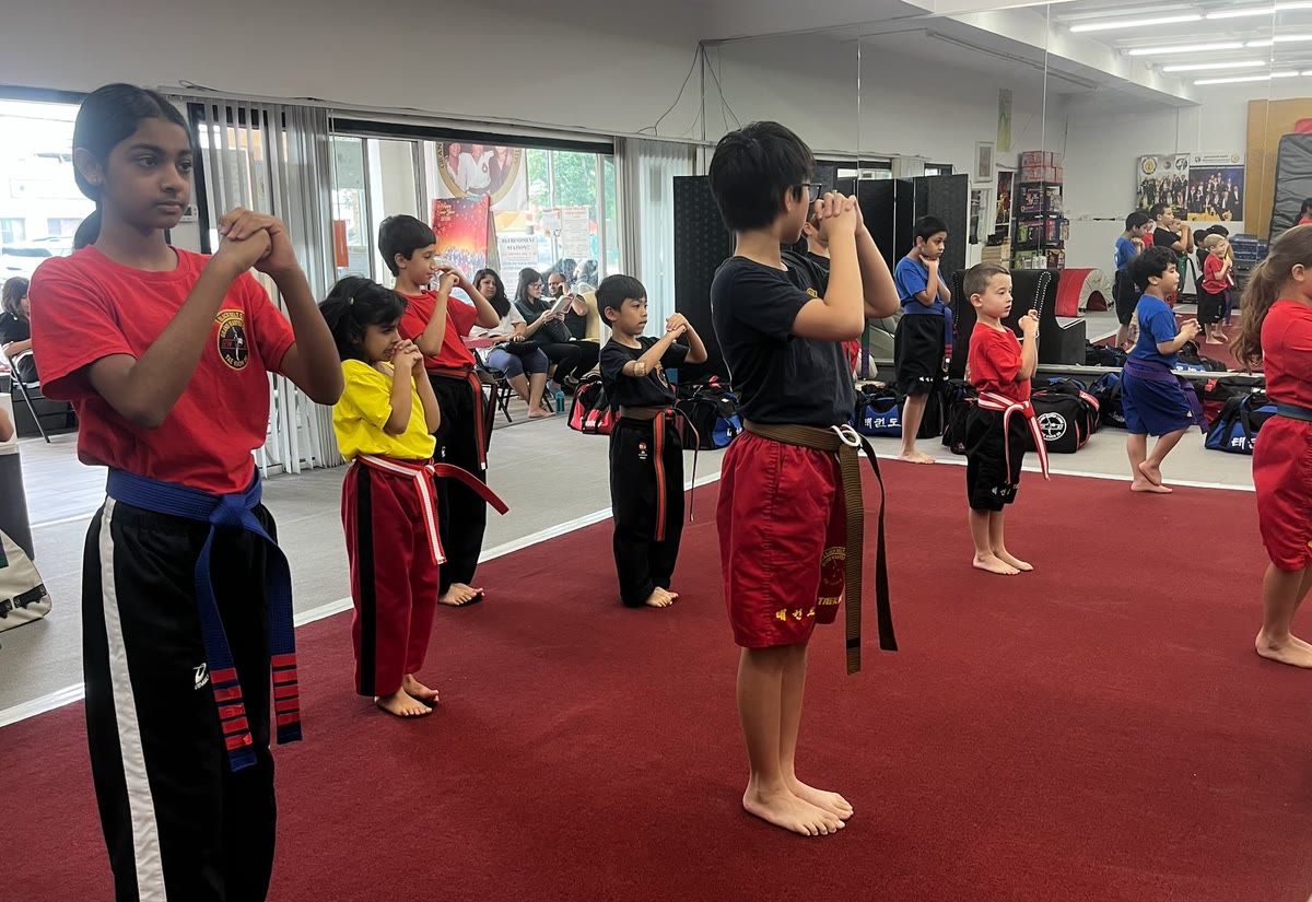 Students stand at attention with stripes taped on their belts, a blue belt with red stripes in front.