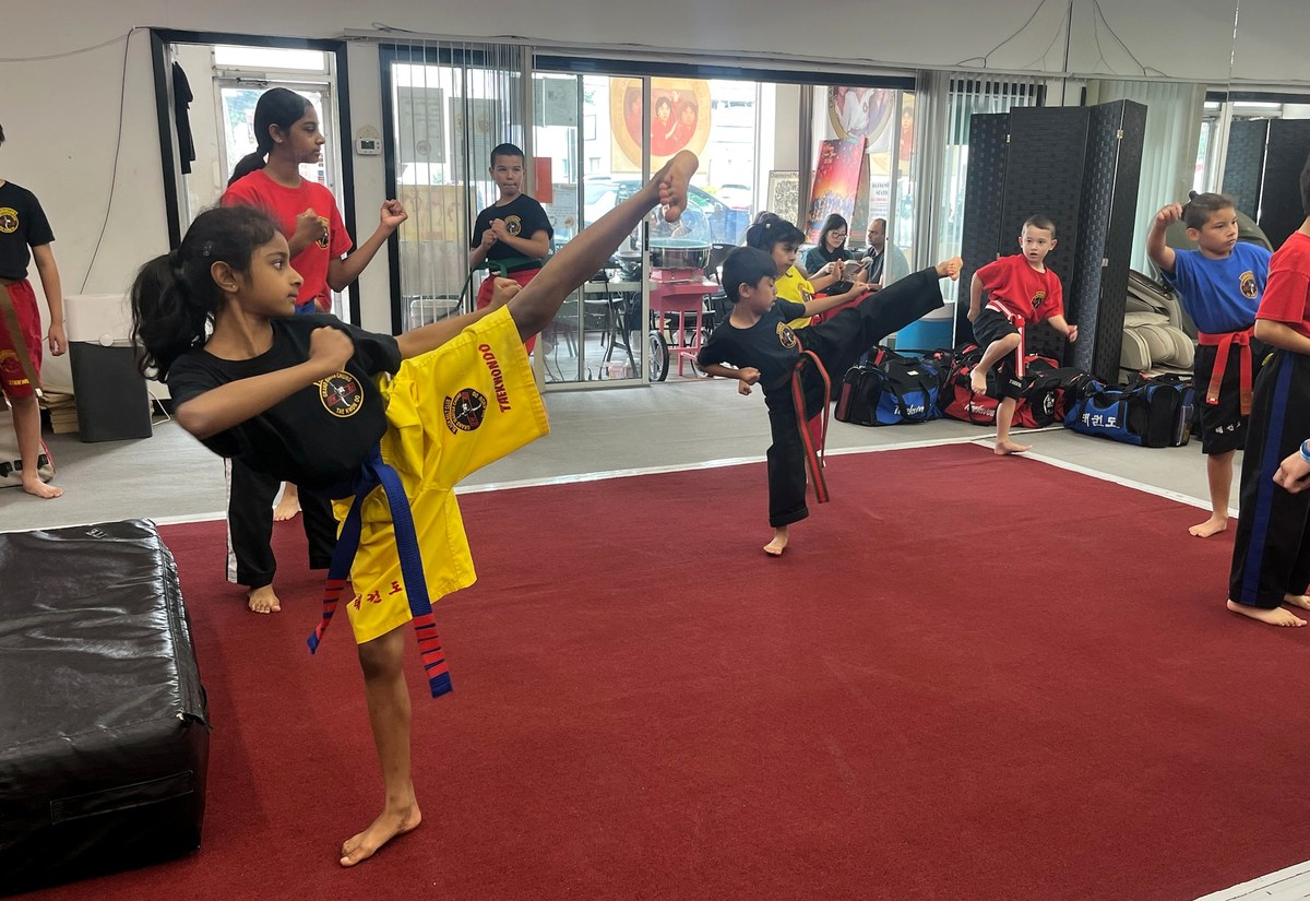 A student executing a high kick during a group martial arts class.